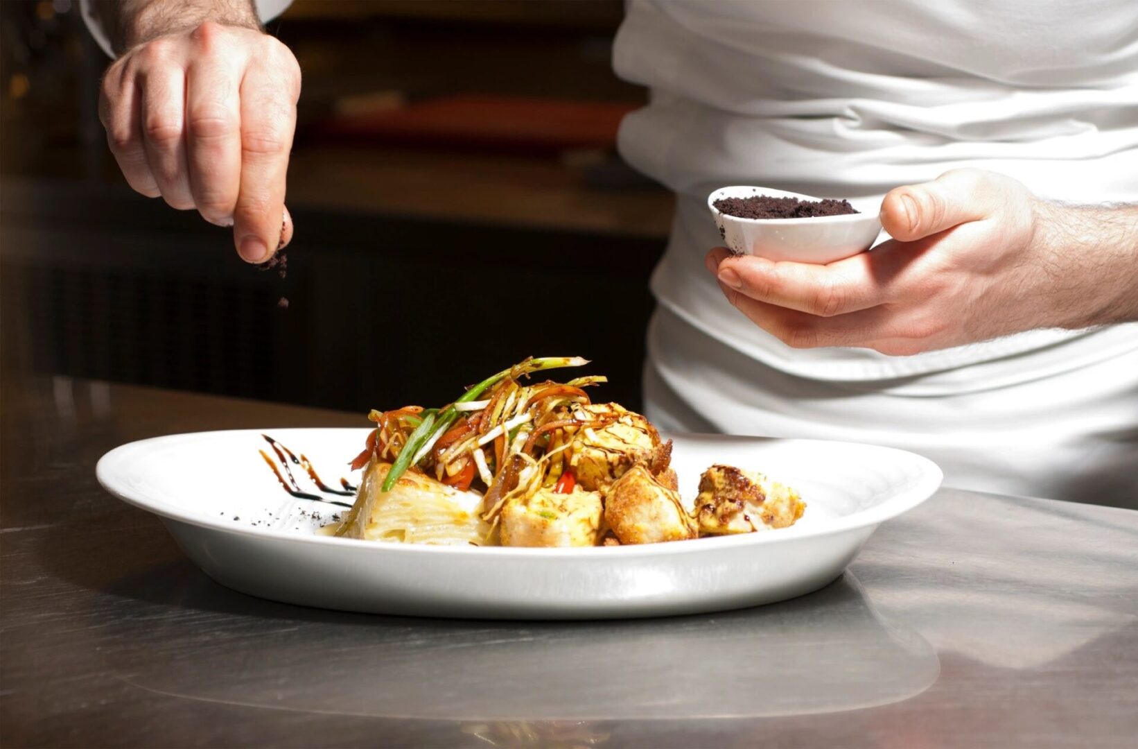 A Chef Sprinkling Seasoning on a Plate