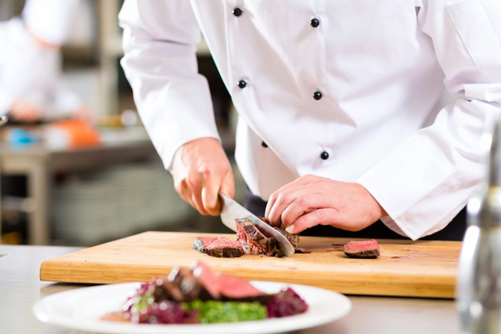 A Chef Cutting Slices of Beef on a Chopping Board