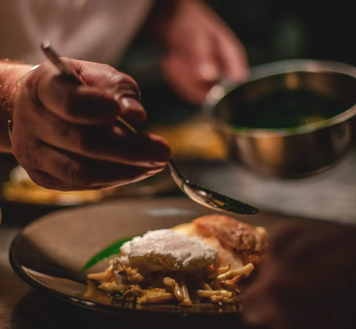 A Chef Adding Sauce to a Pan of Food