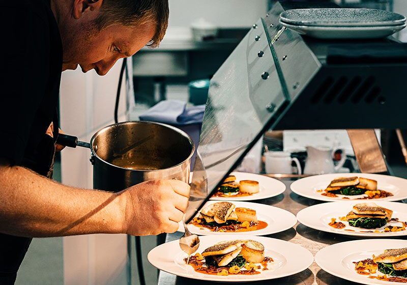 An Image of a Chef Pouring Sauce onto Plates